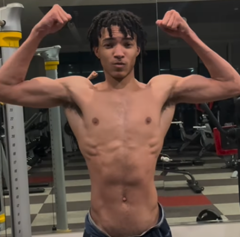 Person flexing muscles in a gym mirror.